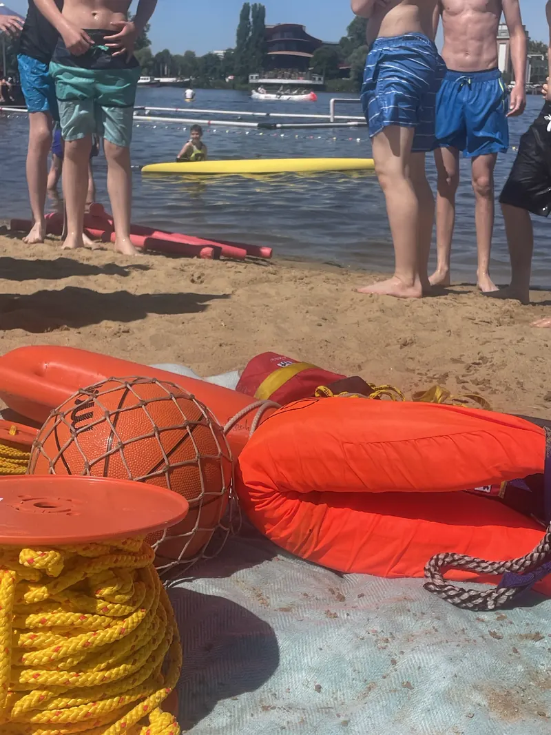 Rettungsmittel, Bälle und Seile am Strand, im Hintergrund der See